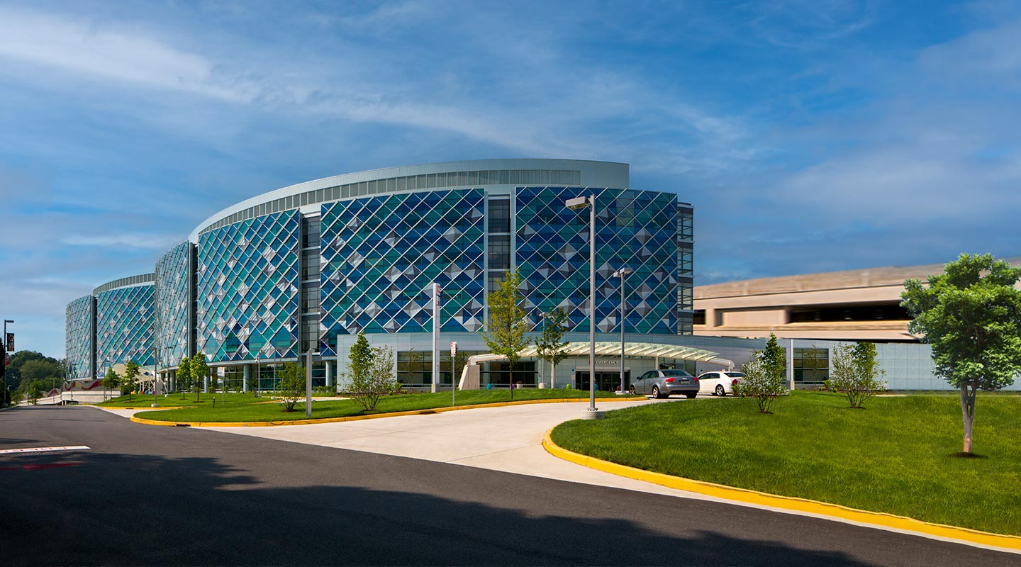 This is an image of the entrance to Nemours Children's Hospital, Delaware on a sunny day and two cars  in the foreground.